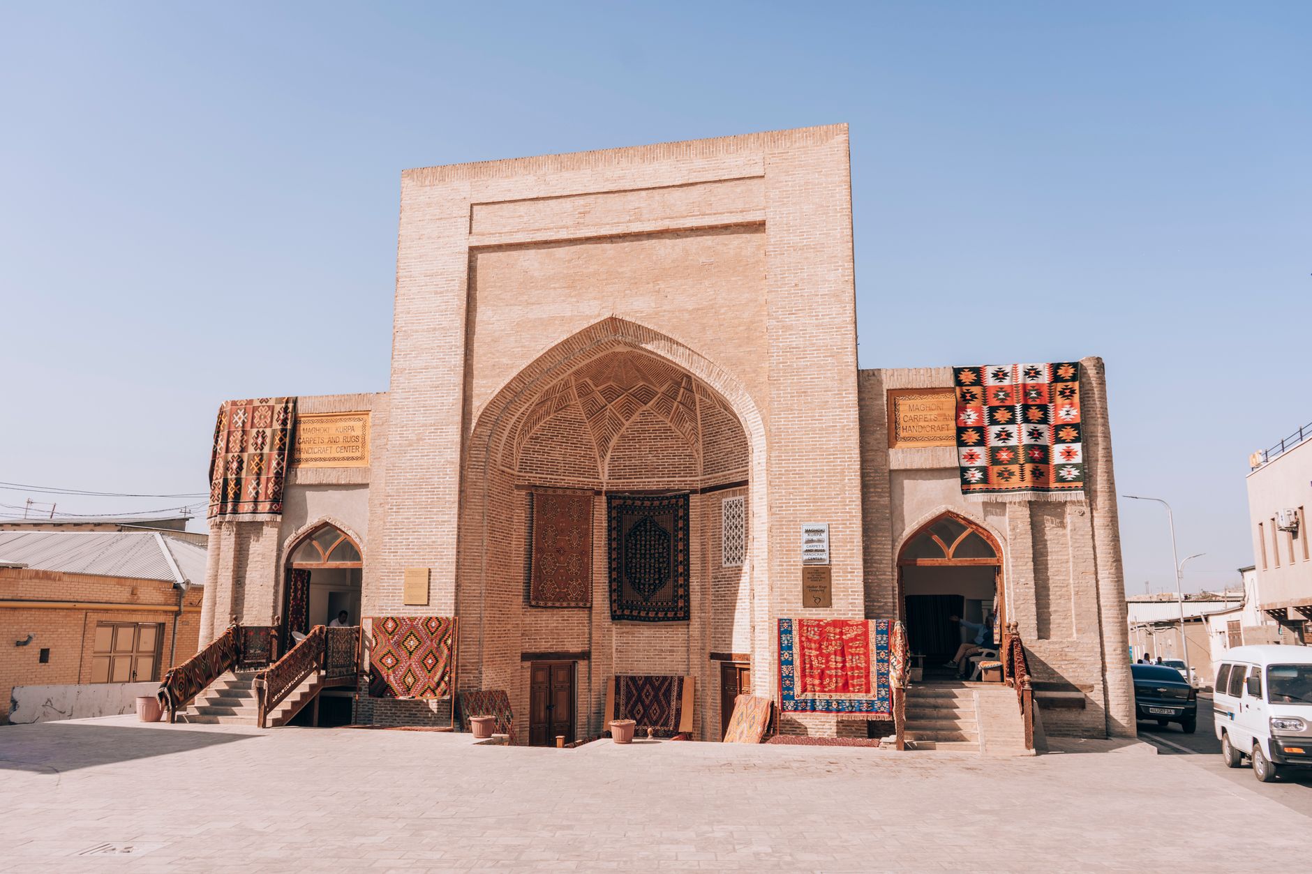 Historic building in Bukhara showcasing Uzbek carpets and textiles under a clear sky, Uzbekistan