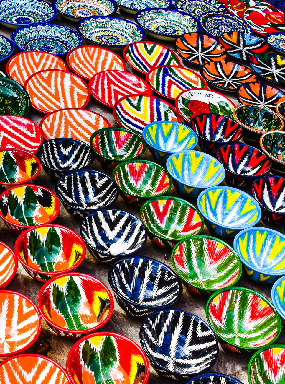 Vibrant display of handmade ceramic bowls in Bukhara, Uzbekistan market
