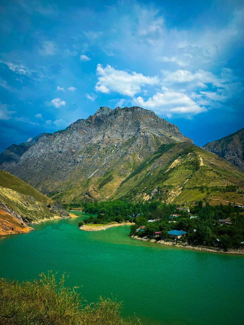 Stunning landscape of Lake Charvak with its turquoise waters and towering mountains under a bright blue sky · Fergana Valley, Uzbekistan