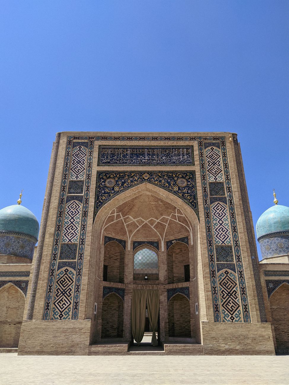 A historic mosque's facade with blue domes under a clear sky · Karakalpakstan, Uzbekistan