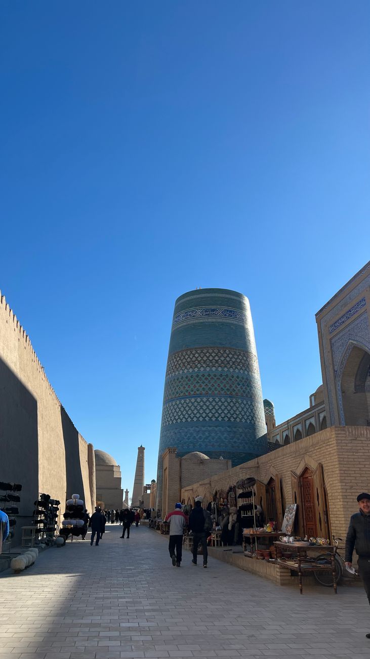 Exploring the historic streets of Khiva with the iconic Kalta Minor Minaret under a clear sky, Uzbekistan