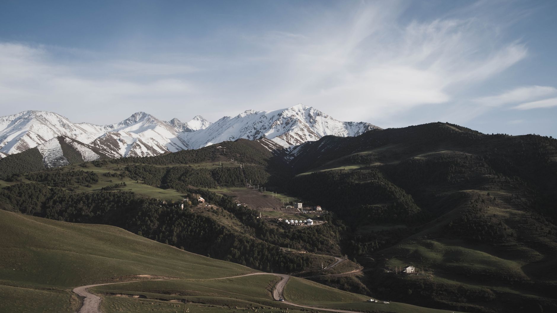 Serene landscape of snow-capped mountains and yurts in Kyrgyzstan's expansive countryside · Chimgan & Charvak, Uzbekistan