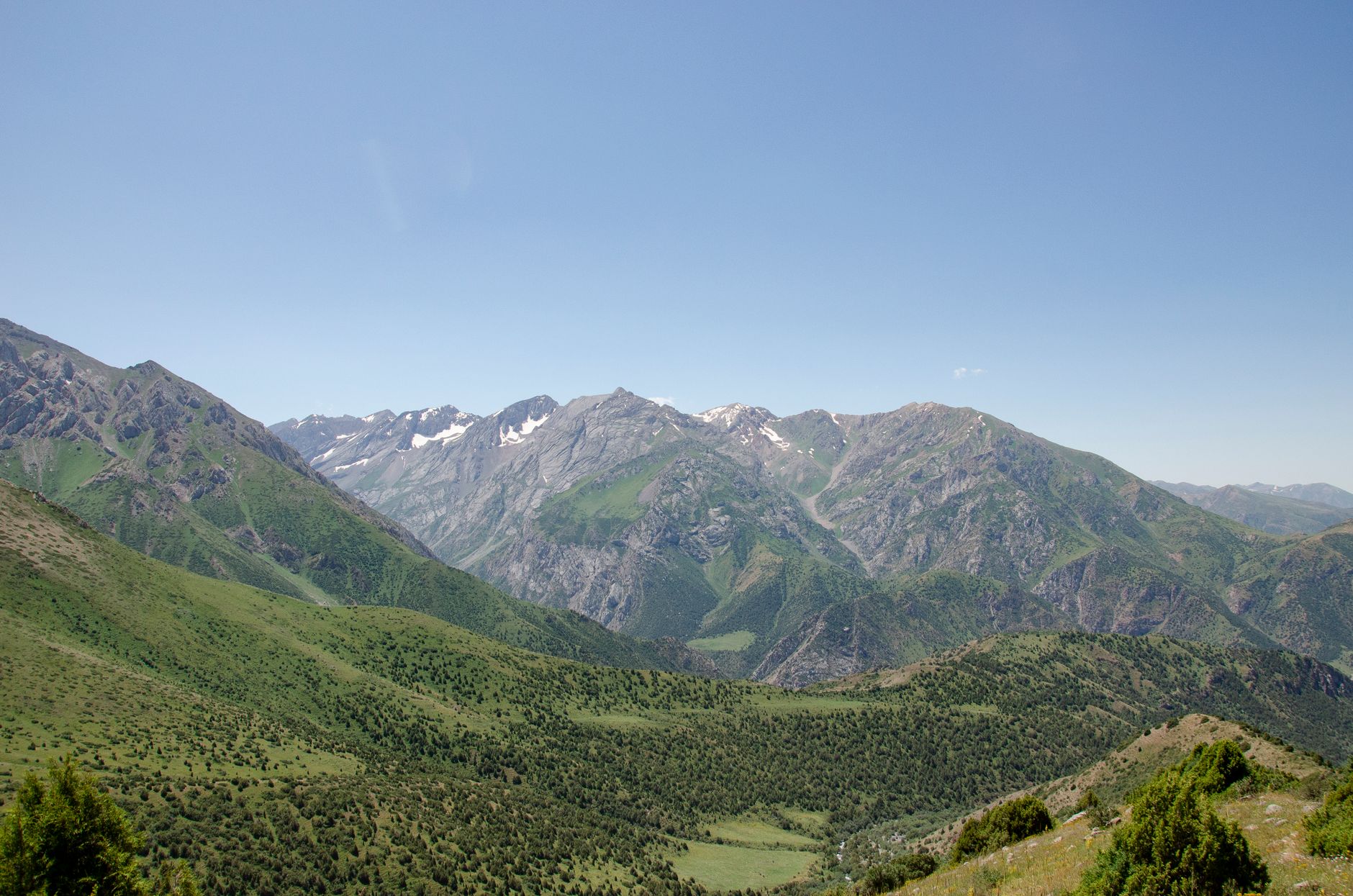 Panoramic view of lush green mountains near Shymkent, Kazakhstan, under a clear blue sky · Chimgan & Charvak, Uzbekistan