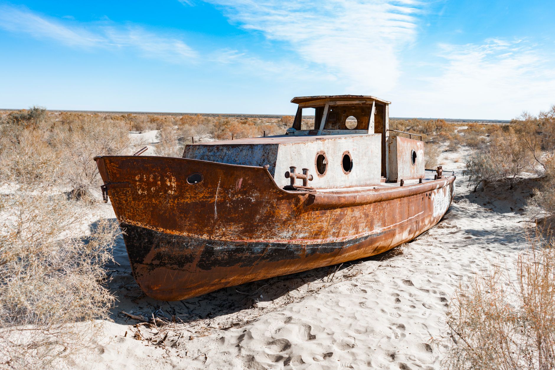 Abandoned rusty ship stranded in the sands of the Aral Sea desert in Uzbekistan, symbolizing drought and ecological change · Muynak & the Aral Sea, Uzbekistan