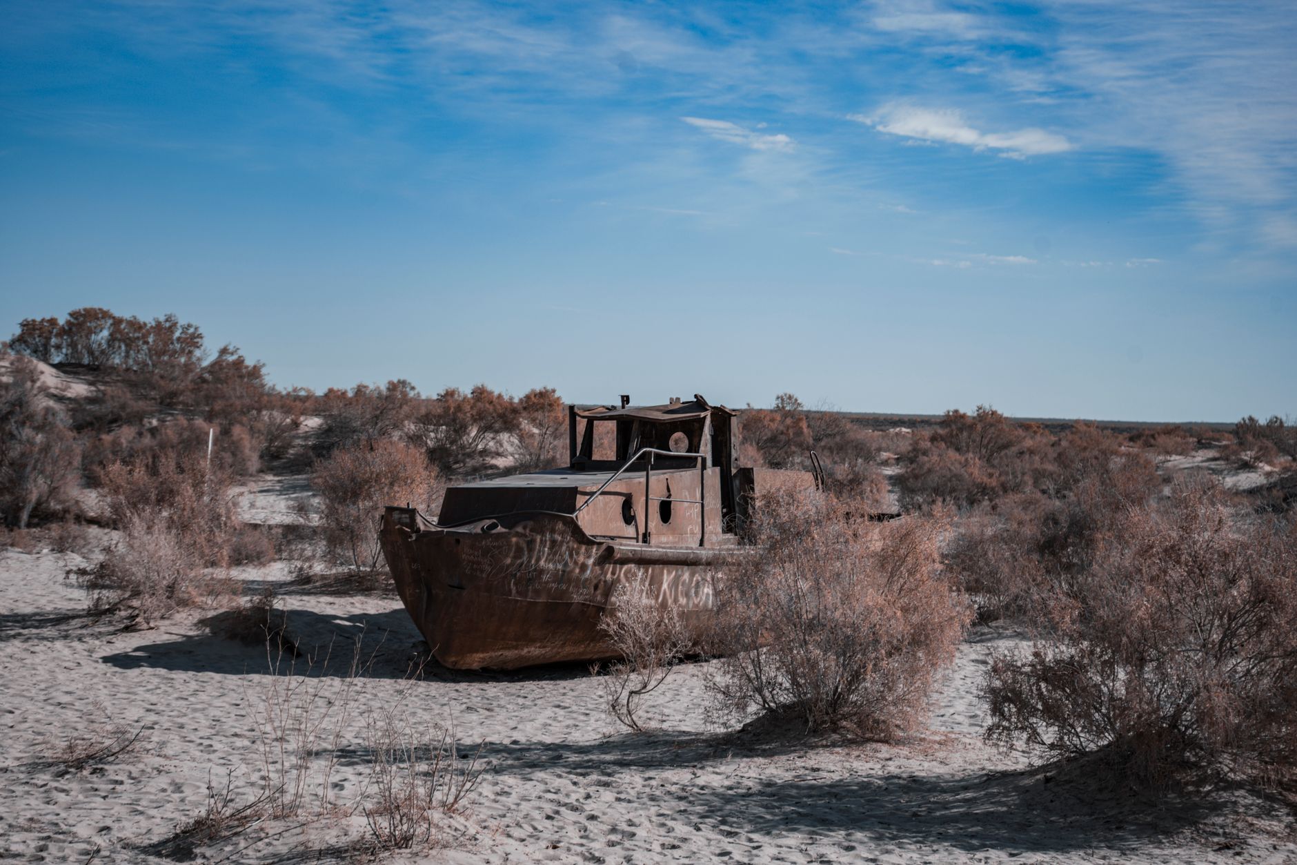 An old, rusting ship stranded on the desert sands of the Aral Sea under a bright blue sky · Karakalpakstan, Uzbekistan
