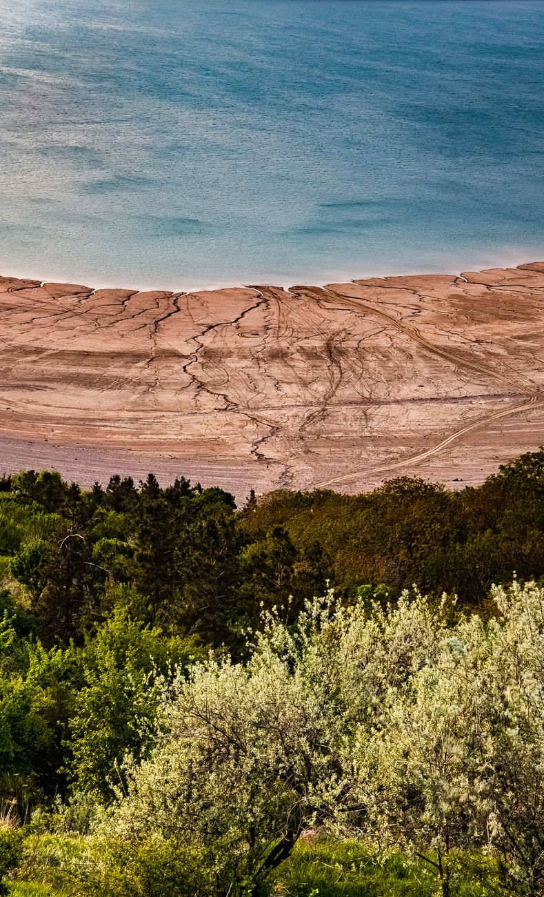 Landscape of a serene lake and rugged shoreline surrounded by lush green foliage · Nurata & Aydarkul, Uzbekistan