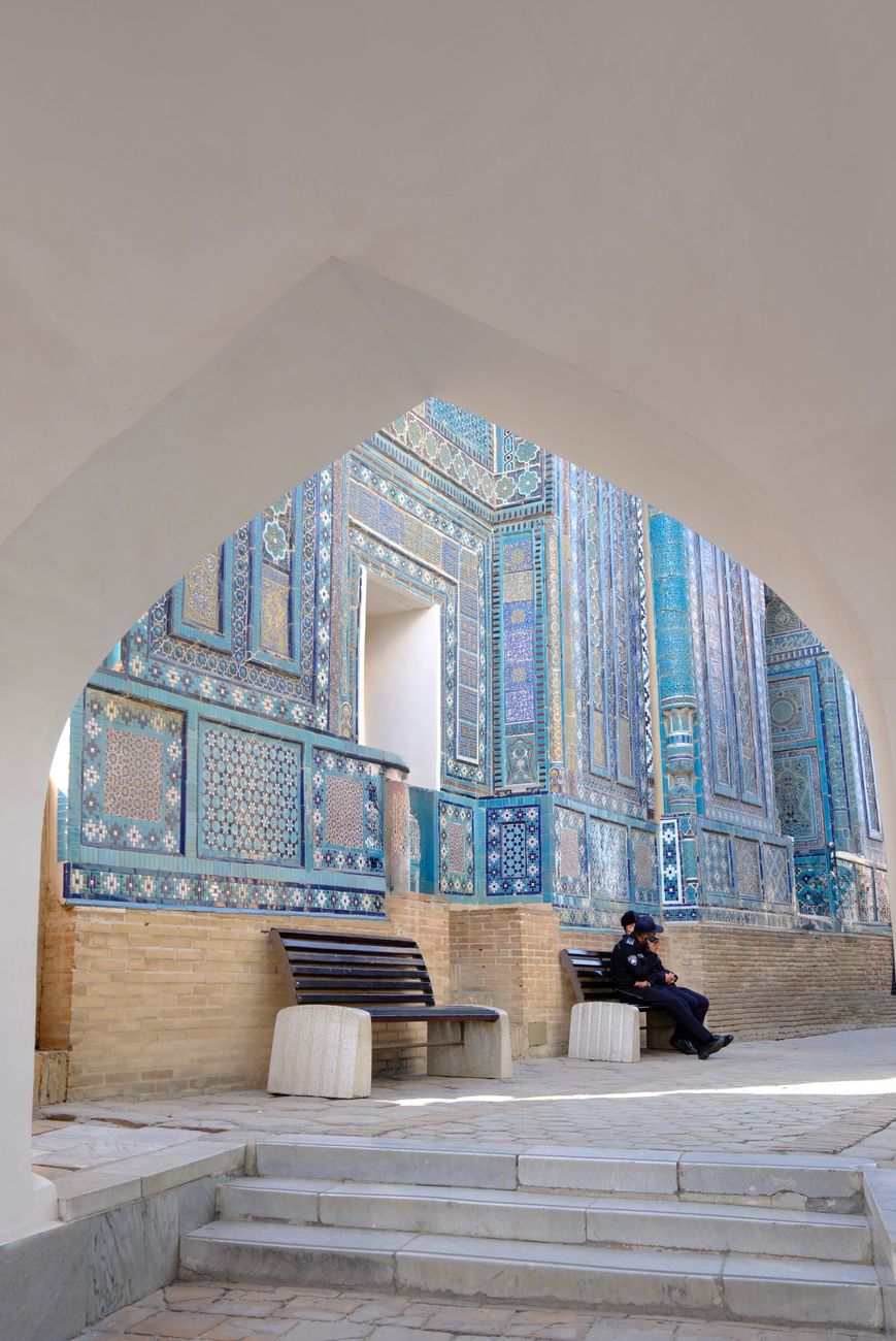 A person relaxes on a bench at a historic architectural site with intricate tile work · Samarkand, Uzbekistan