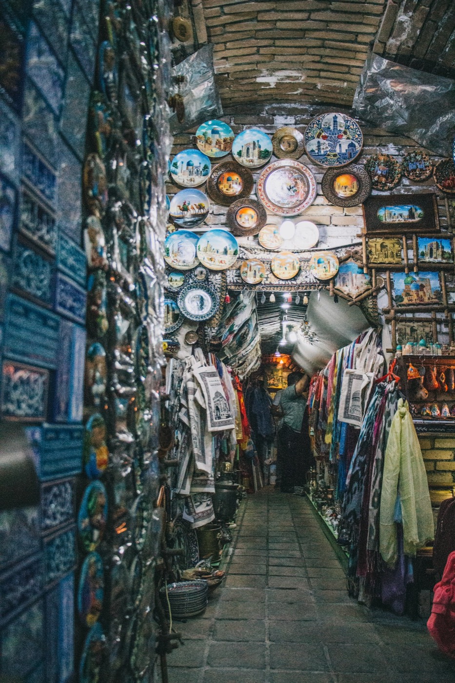 Vaulted brick alley in Samarkand with painted plates, ikat scarves and hanging ceramics