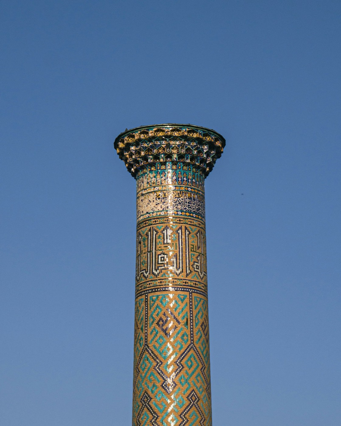 Detail of muqarnas capital and calligraphy band at the top of a Samarkand minaret