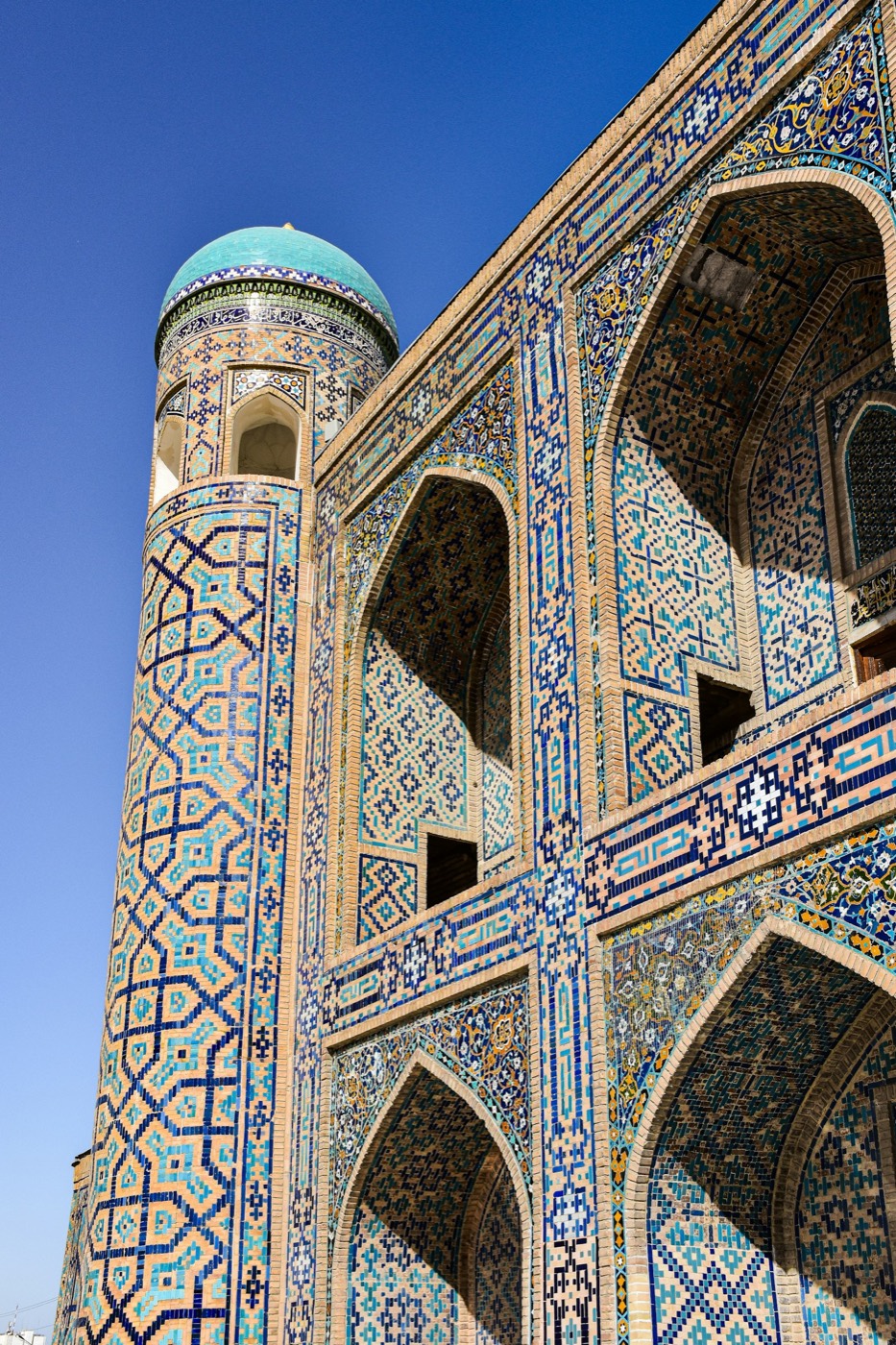 Corner minaret and iwan of a Registan madrasa in Samarkand with dense majolica tilework